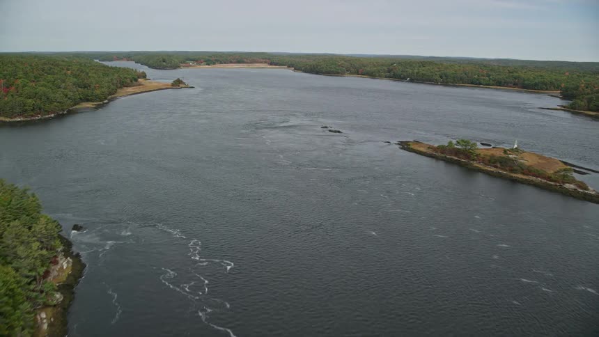 Aerial of a small island in the middle of the river with forest in the surroundings