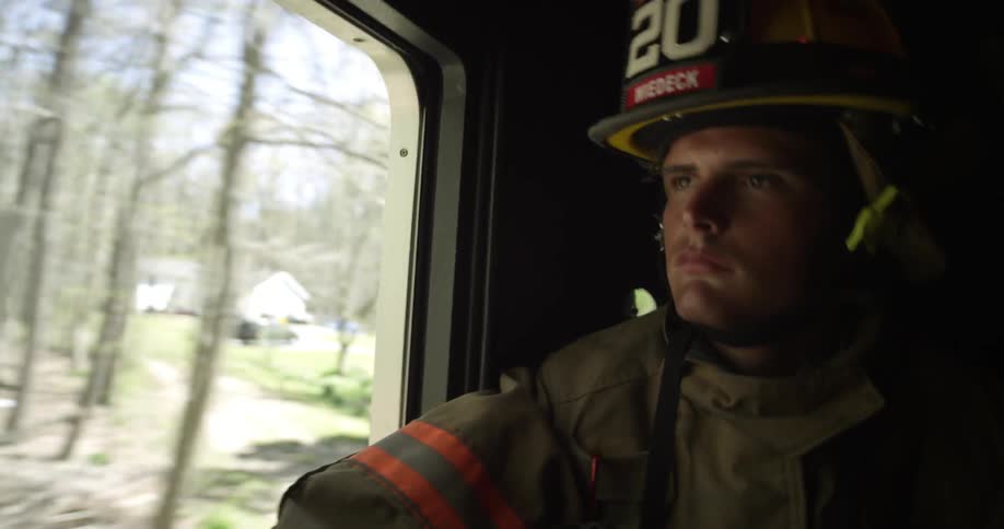 A firefighter rides in a truck looking out the window