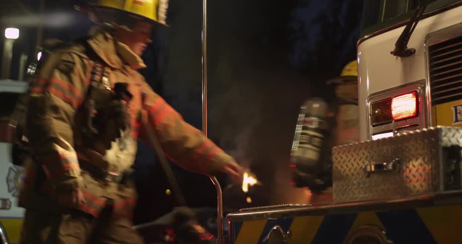 A firefighter walks to the truck and opens one of the compartments
