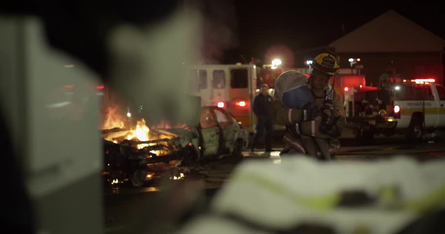 Fireman takes boy away from car fire towards paramedics