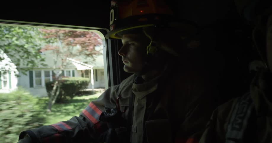 Two firemen ride in a firetruck