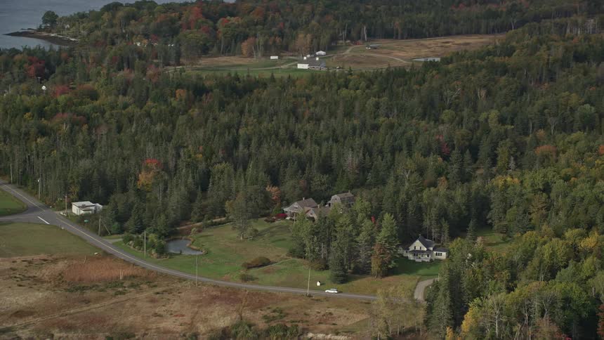 Aerial view of a few houses in the countryside next to a lake