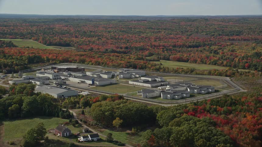 Aerial panorama of a prison in a natural setting surrounded by trees and a lake