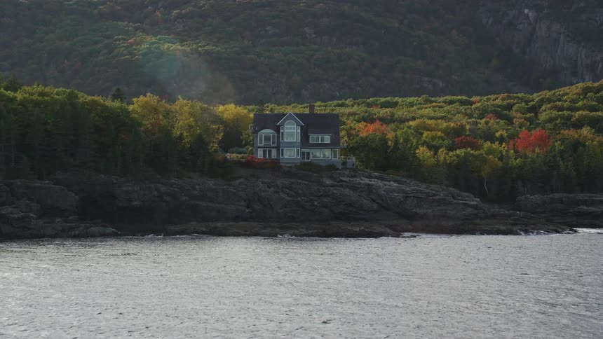 An aerial view of a secluded rural home near a coastal cliff in fall