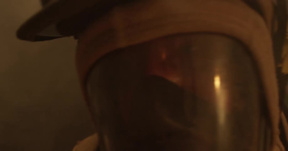 A firefighter is moving through a smoke filled room