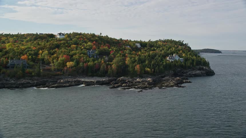 A house on an island facing the sea and surrounded by trees