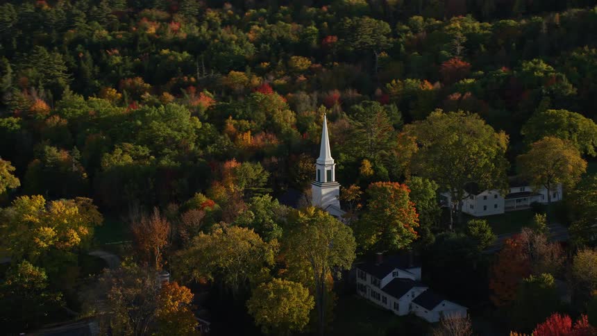 Aerial panorama of a church in the midst of a quaint town surrounded by forested areas