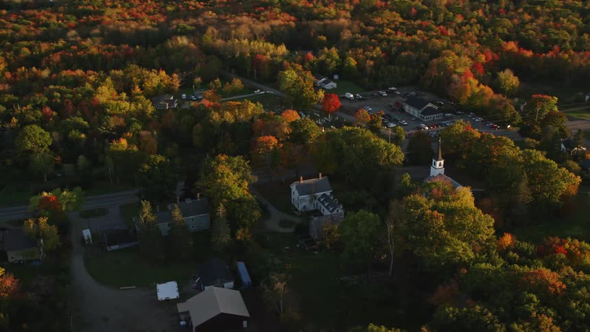 Aerial view of a town surrounded by red and brown trees