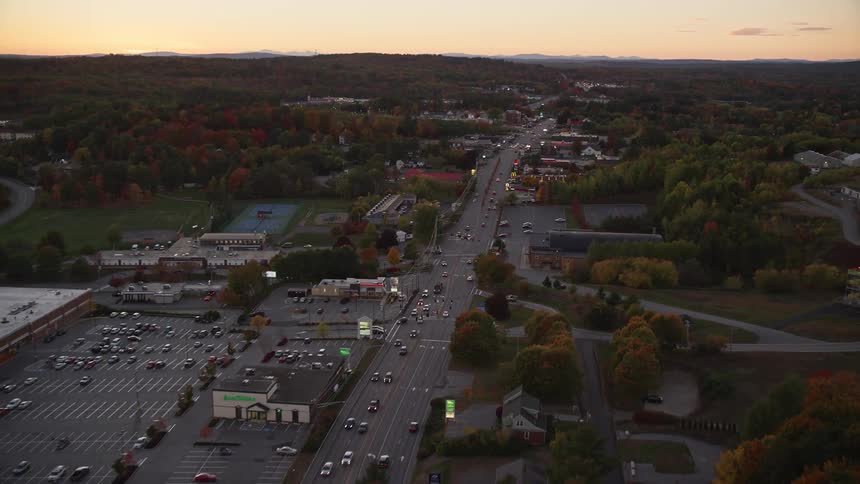 Aerial view of a parking lot and cars driving on a highway at dusk