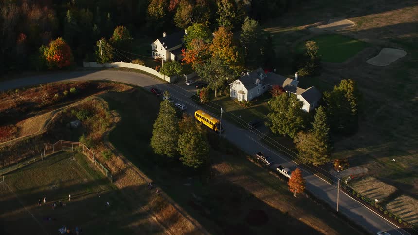 A rural region with a house and in front of it there is a yellow bus parked