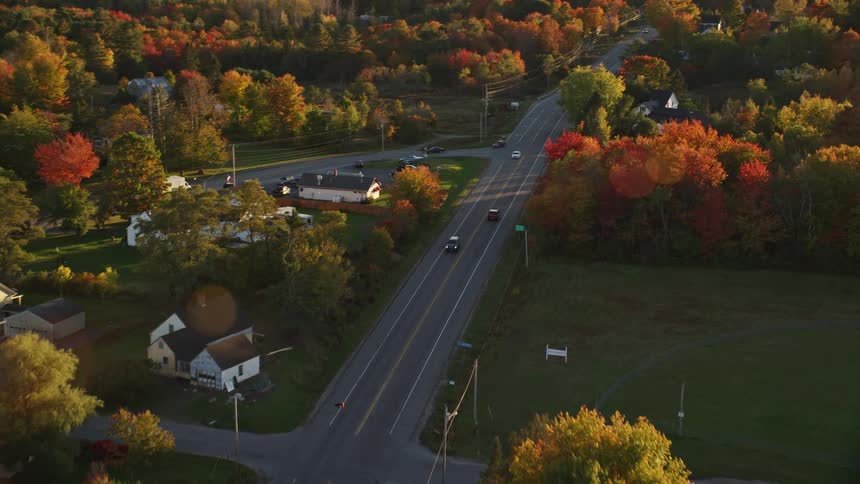 Aerial of a red car driving through a rural community during autumn