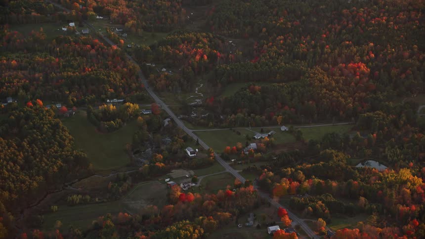 Aerial of a rural town surrounded by trees at sunset
