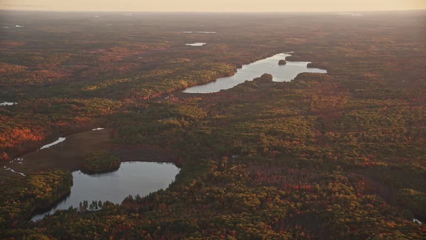 Two large lakes in the middle of forests of trees in an autumn with sunlight