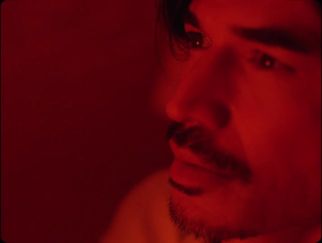 A scared man with a mustache looking up in red lighting