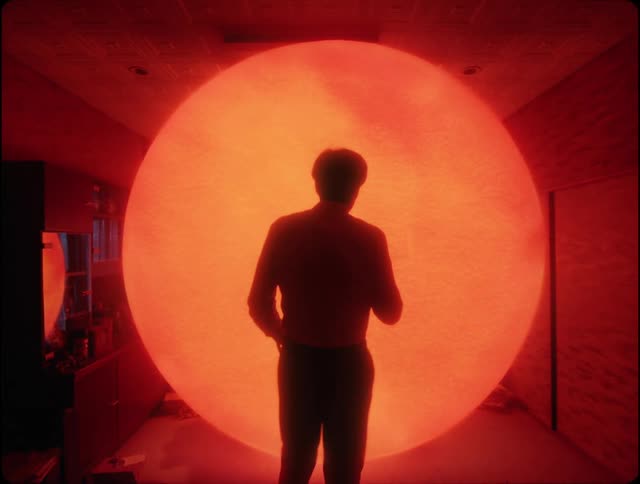 Glowing sphere changes color as it grows toward standing man