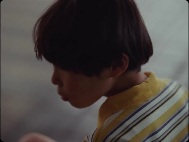 Boy with chaps striped polo shirt looks over his shoulder