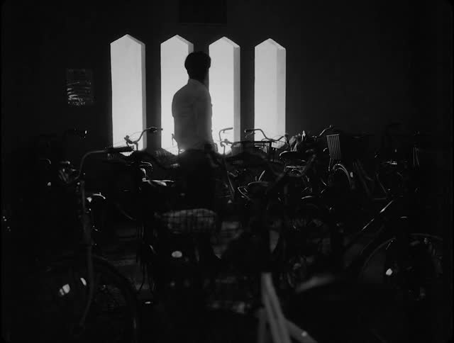 Man walking on the street at night looks at a person made of light through a window