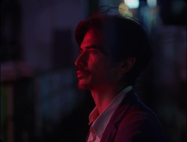 Face of a man in the city streets under red lights