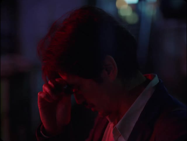 Face of a tired man in the city streets under red lights