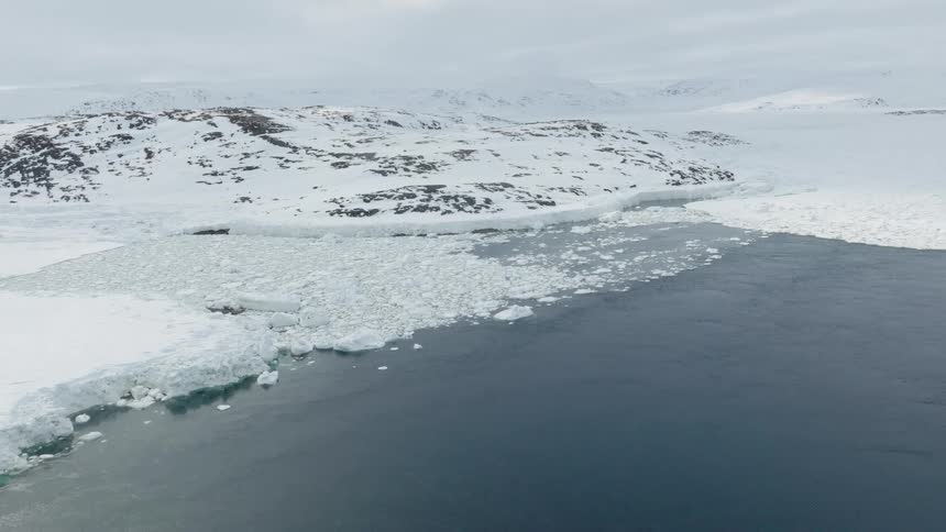 In the actic ice and snow are covering the mountains close to the sea