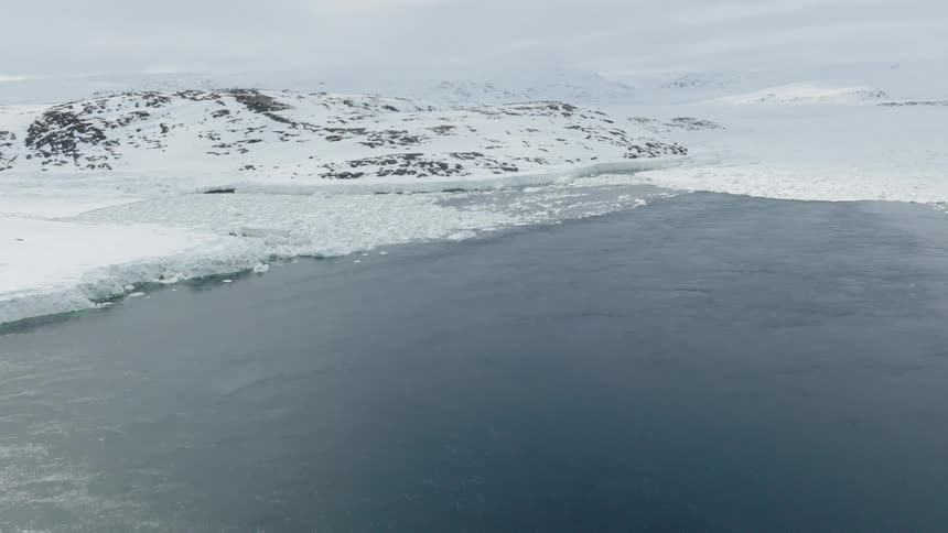 Slush floats near snow covered coast during winter