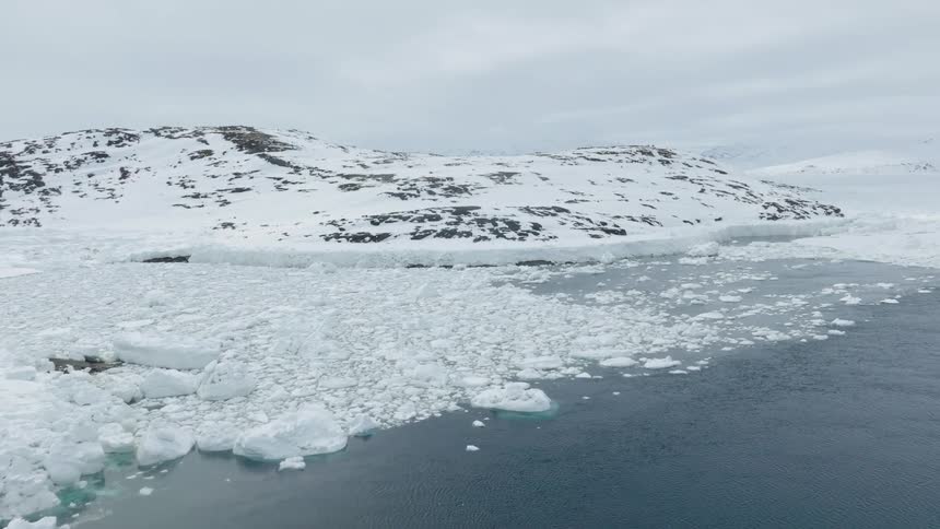 A mountain in an arctic region covered in ice on land and sea