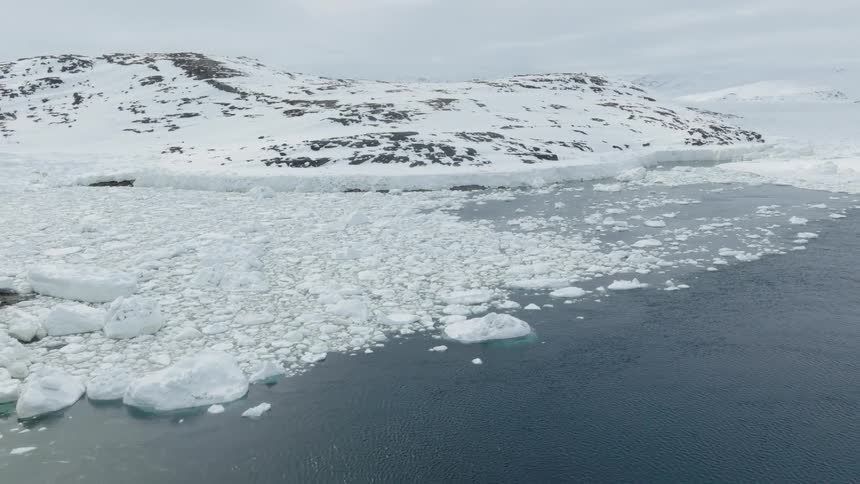 Aerial view of floating ice in the coast next to a mountain