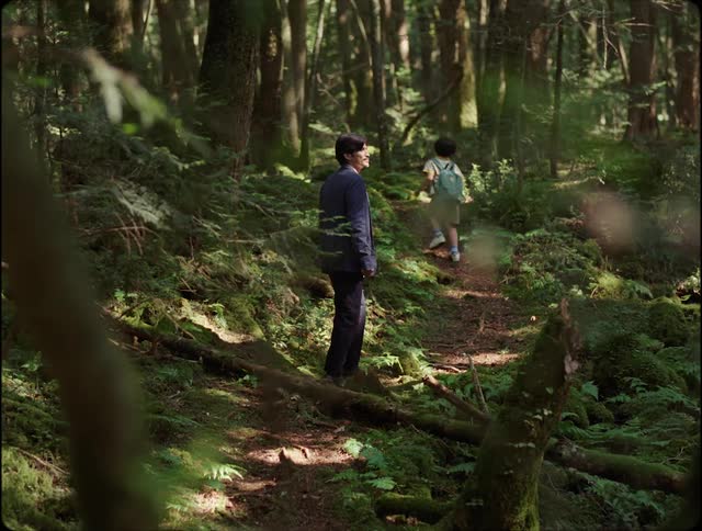 A man and child hike in the forest