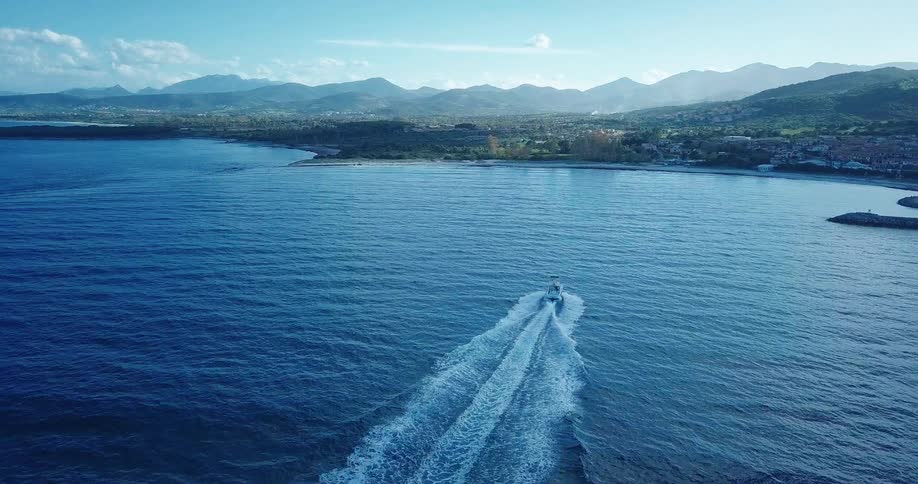 Aerial panorama of a boat heading towards a coastal city on the horizon