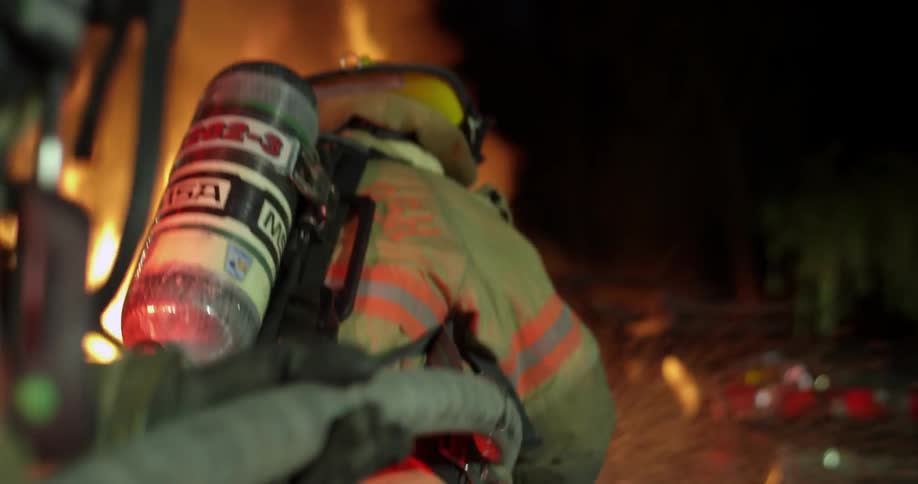 Firefighters are using a hose on a burning car