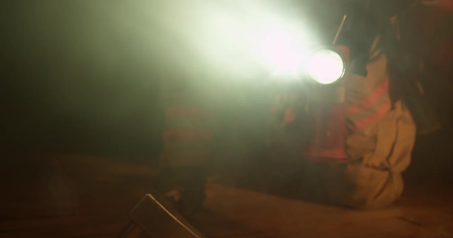 A firefighter is crawling through a burning home
