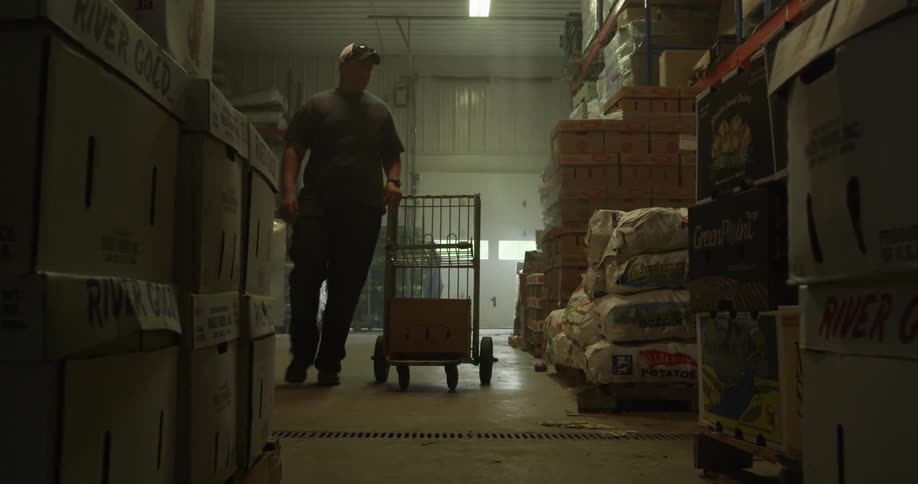 People are working in a warehouse rolling carts and loading them