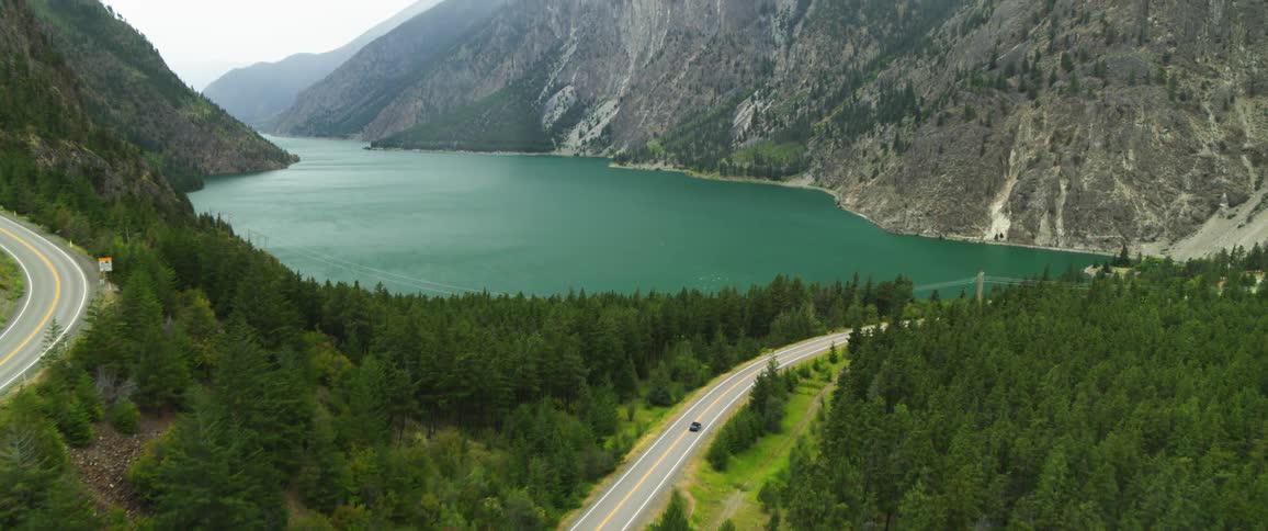 Aerial view of a road by a lake amidst the mountains
