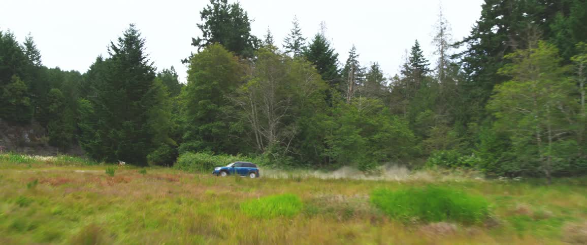 Car drives down dusty roads through forest