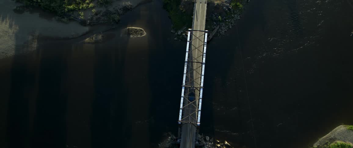 A car passing by a bridge with steel on its side