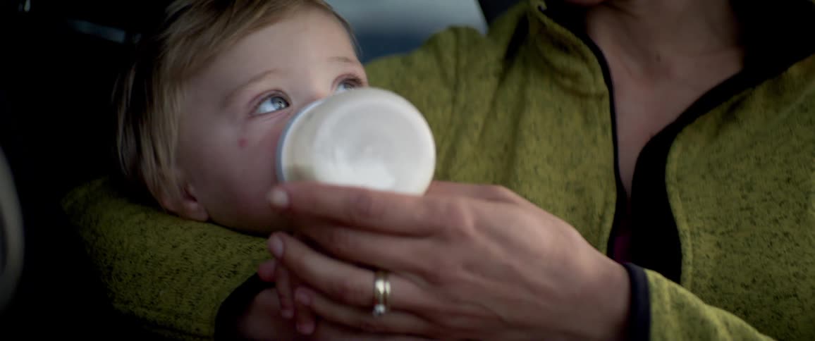 A mother breastfeeding her daughter inside a car