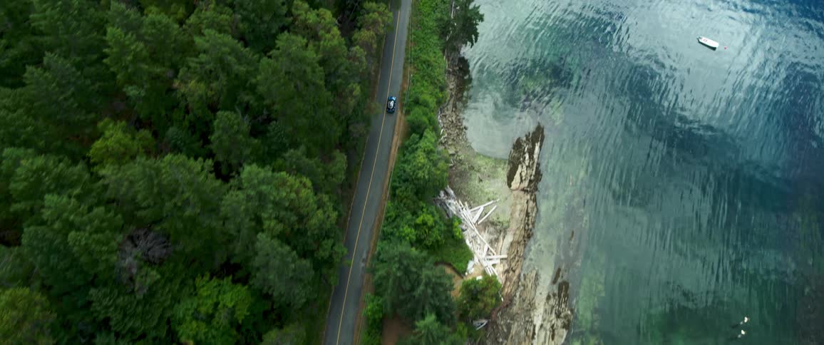 Aerial view car drives on a road next to the coast