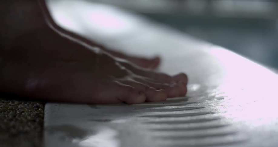 A person walking barefoot on the edge of a pool