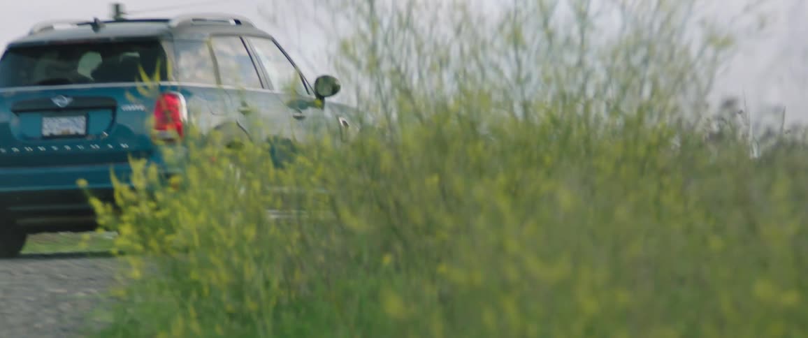 Blue car drives uphill on a cloudy day