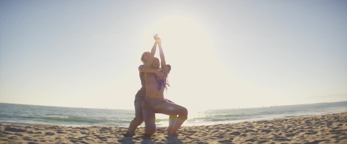 Two female dancers perform together on beach on a sunny day