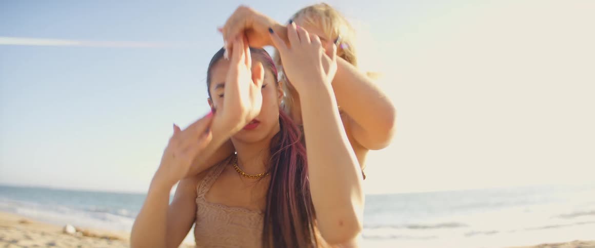 Two women dance near the ocean at daytime