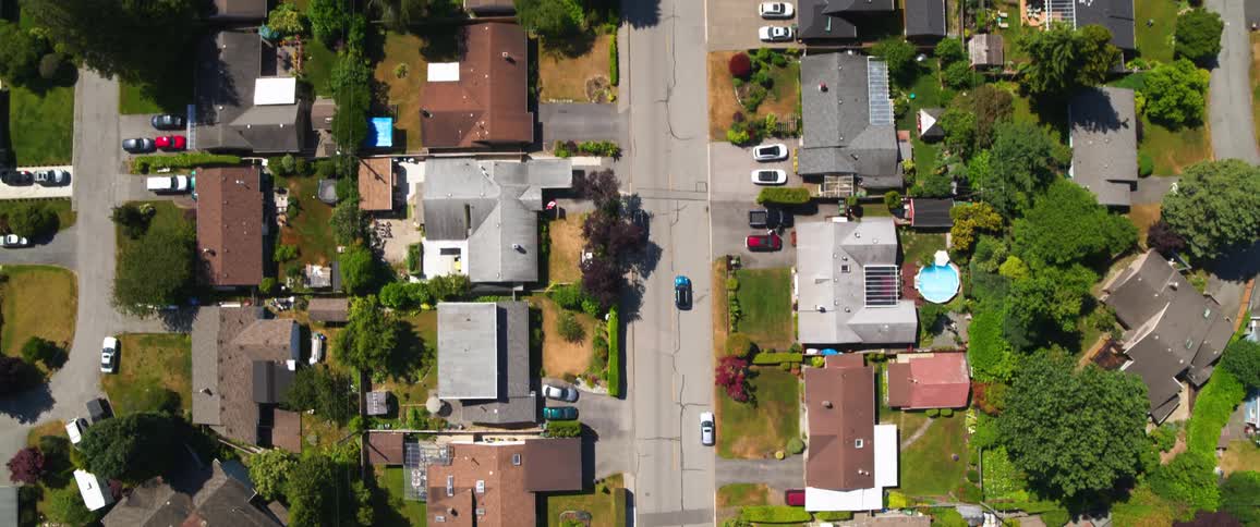 Area view of a residential are with buildings surounded by green vegetation and a car moving along the road