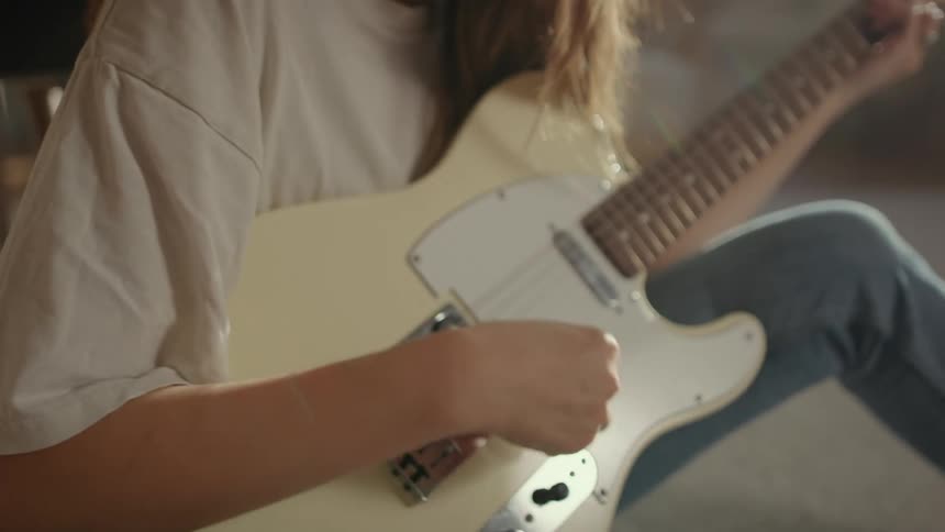Woman sitting on the floor plays electric guitar