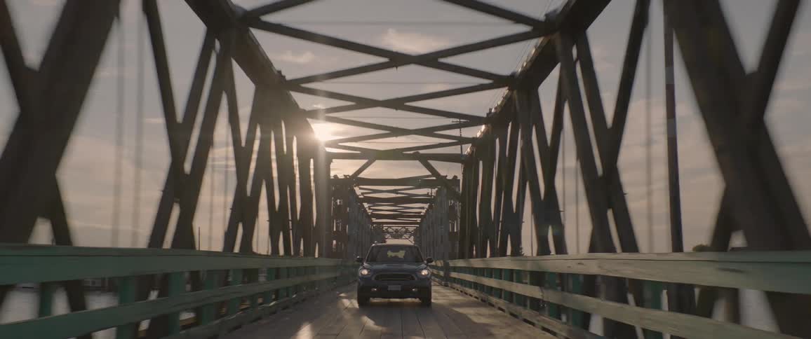A car driving on a wooden bridge with iron arches