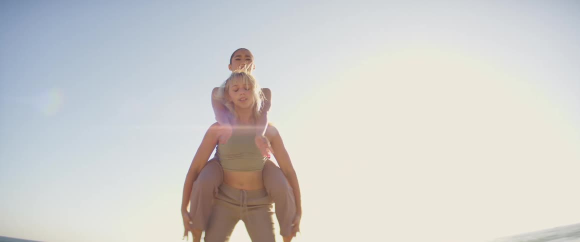Two women do acrobatic movement outdoors