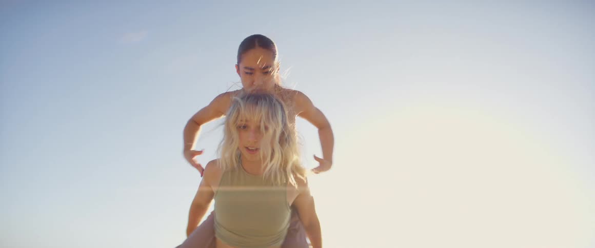 A woman is balancing and dancing on another woman