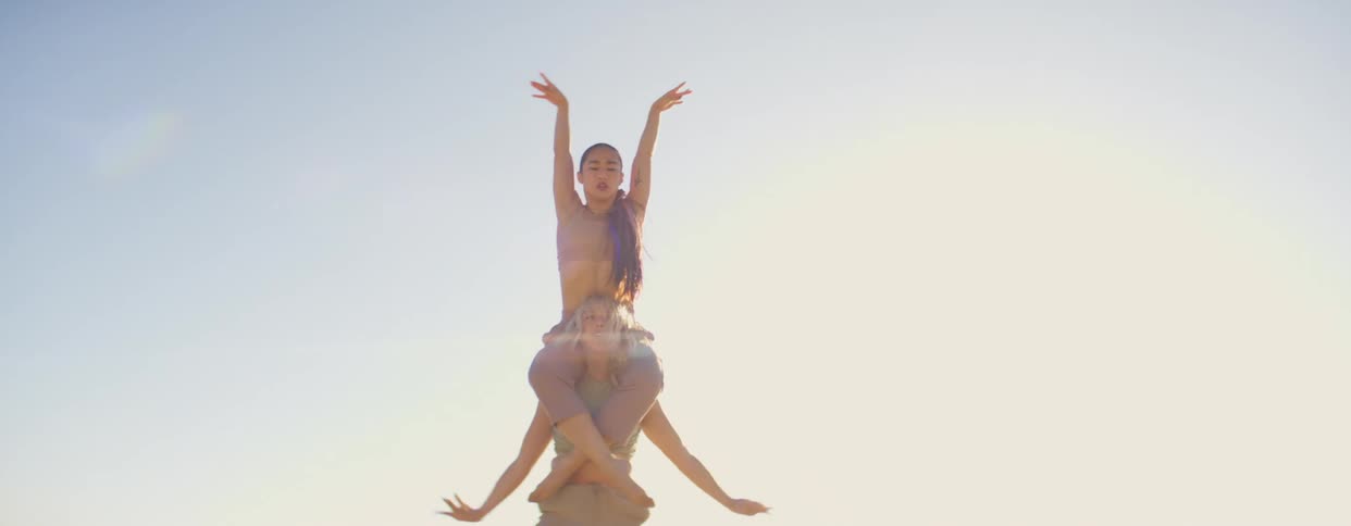 Two women dance on the beach near the sea with the bright sun shining