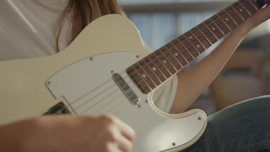 A person playing the guitar sitting on the floor