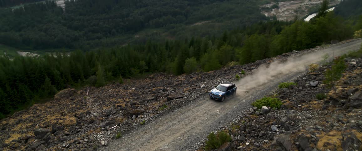 A car is driving on the dirt road by the river