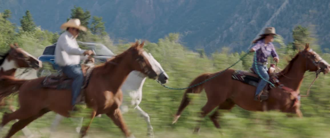 Person in car films cowboys on horses near mountains